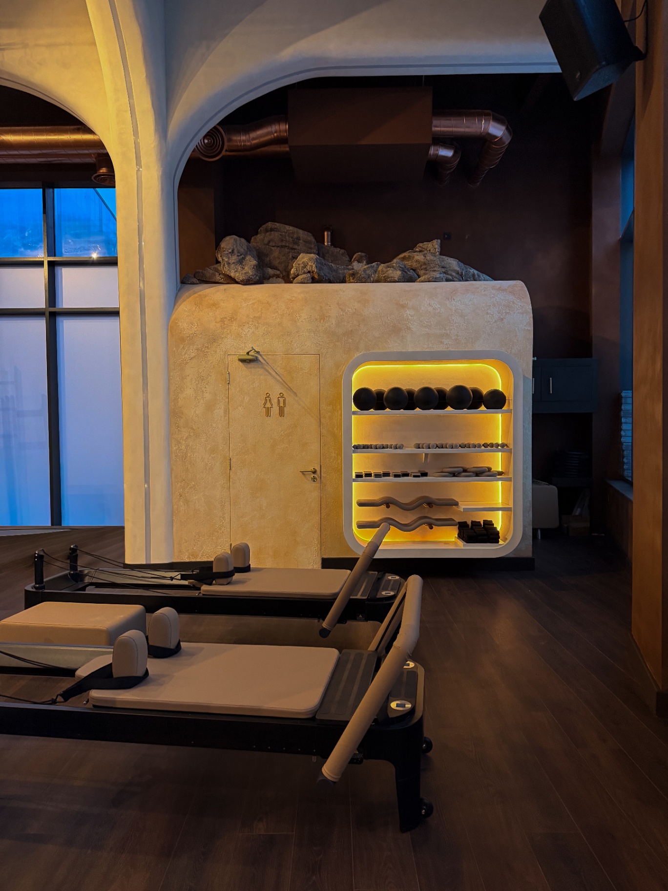 Reformer equipment and amber-lit shelving, reformer Pilates Bristol